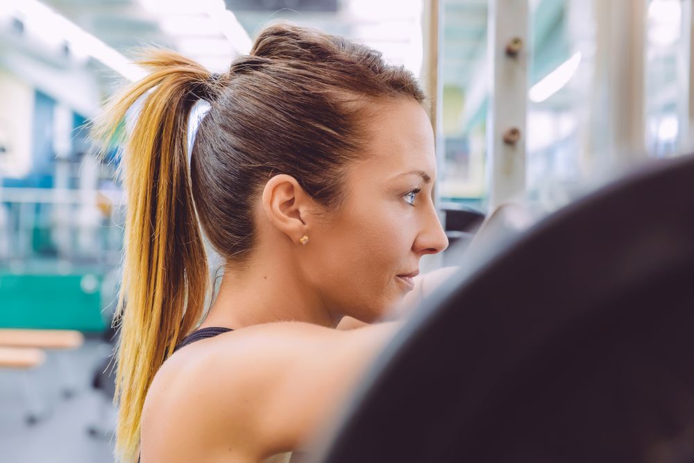 Focused woman standing at barbell