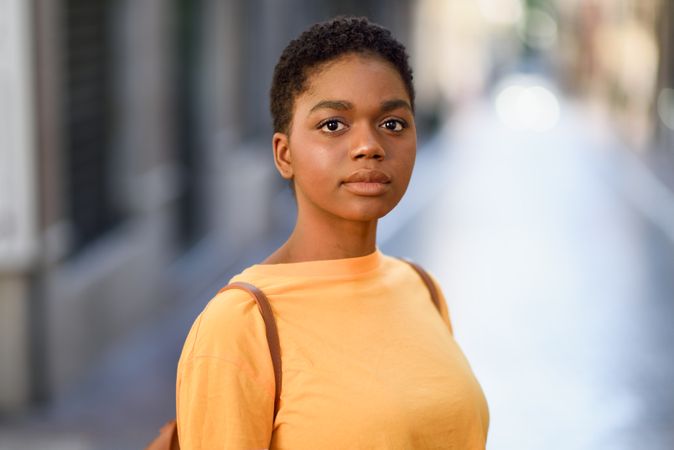 Portrait of female in yellow t-shirt standing on street