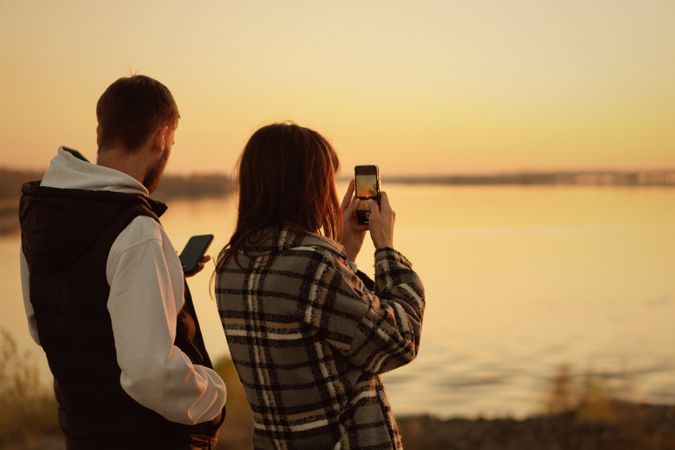 Couple filming sunset on mobile phone