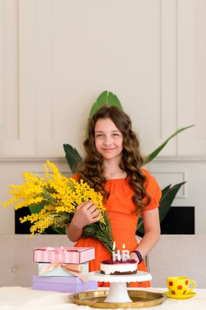 Young girl in orange dress holding yellow flowers