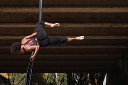 Slim woman doing aerial yoga in city