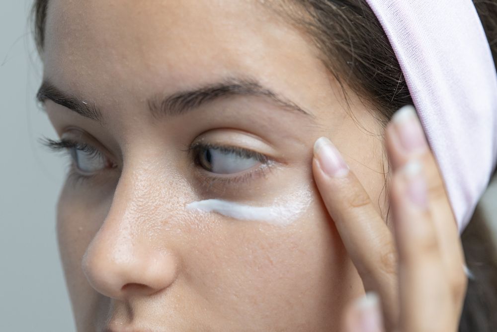 Woman applying under-eye cream for dark circles, a close-up on skincare beauty treatment.
