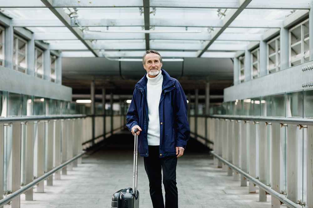 Older man with suitcase standing on walkway