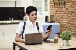 Woman in loft apartment reading her smart phone while working at home