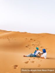 Couple sitting on desert sand 4B7yEb