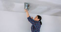 Plasterer smoothing plaster ceiling with the trowel