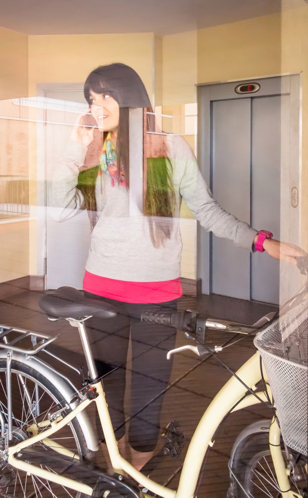 Woman with fixie bike leaving hall behind a glass