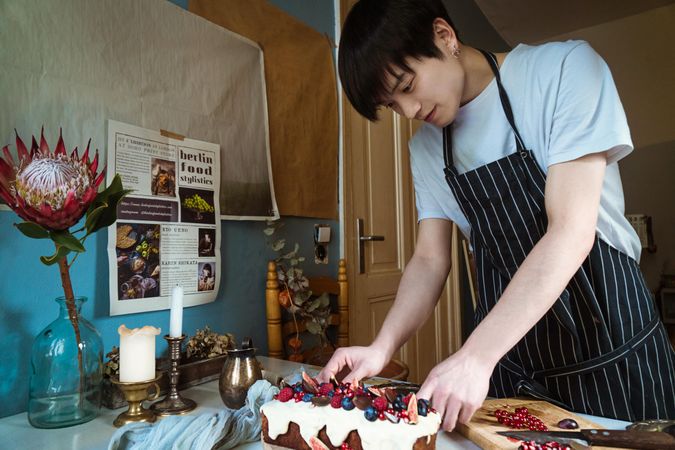 Man wearing an apron and preparing cake in kitchen
