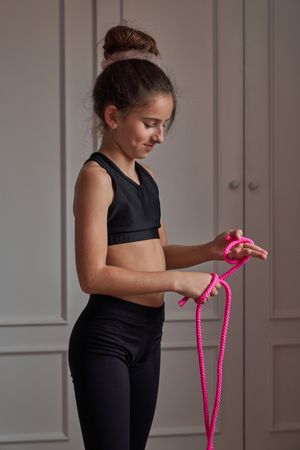 Positive child in sportswear with skipping rope