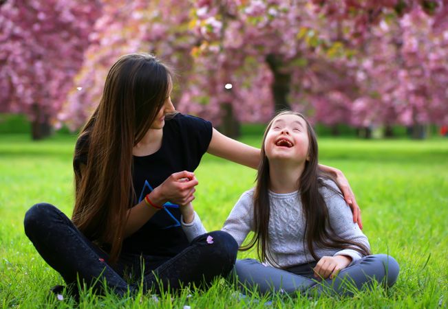 Young child looking up and smiling at flower petals falling from trees