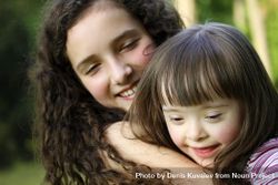 Close up portrait of two adorable sisters snuggling together at the park 5ogKz5