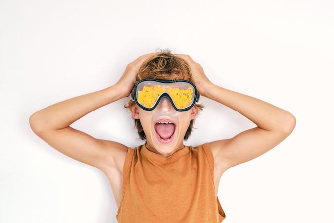 Excited boy in diving goggles with petals touching head while sh