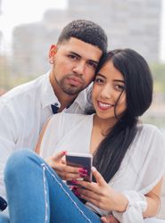 Man bonging smiling woman having fun with smartphone
