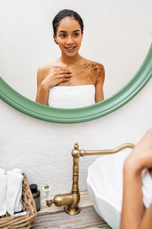 Woman wearing a towel looking in the mirror in the bathroom