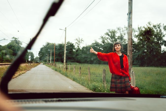 Woman in red sweater catching car on road
