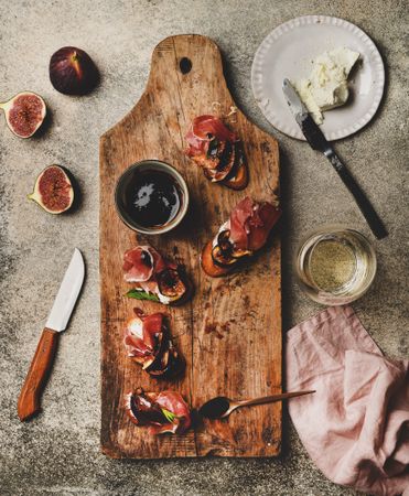 Crostinis with prosciutto, goat cheese and grilled figs on wooden board, square crop