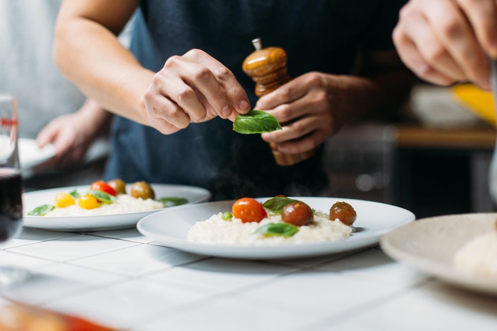Close up of man placing basil on risotto