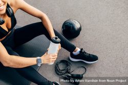 Woman holding water bottle on exercise mat 5XDVv5