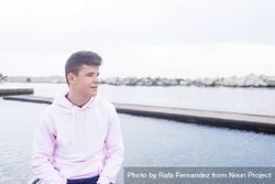 Young male teenager standing on rock breakwater with copy space 4AzJXm