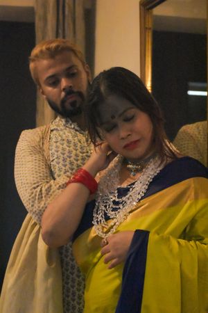 Woman in yellow sari standing in front of man indoor