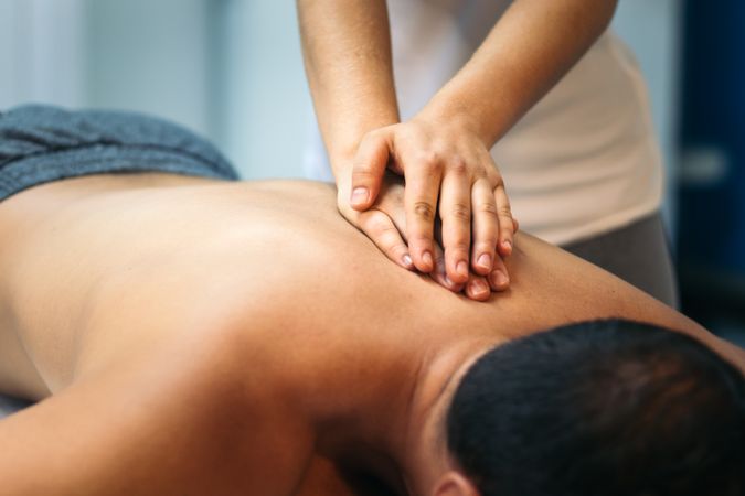 Young woman treating a male patient back. massage physiotherapy. close-up