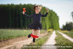 Happy girl jumping with red flowers in her hand bYZVD0
