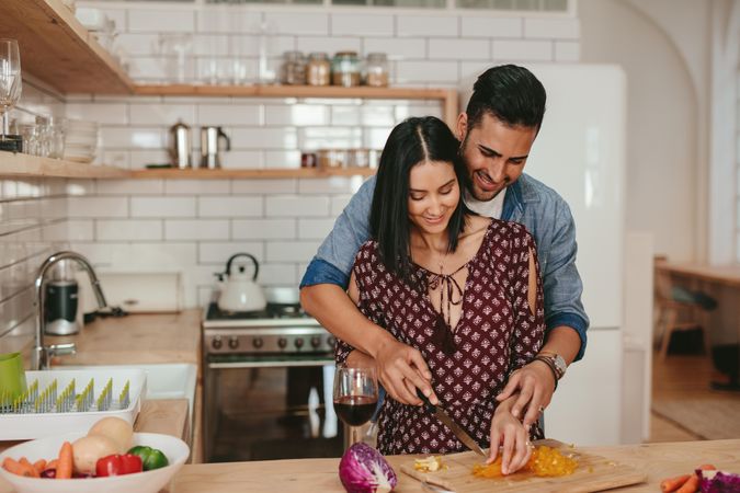 Romantic young couple chopping vegetables together in kitchen