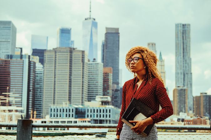 Professional Black female holding her notebooks with Manhattan in the background