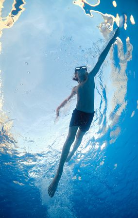 Boy in goggles swimming in transparent water