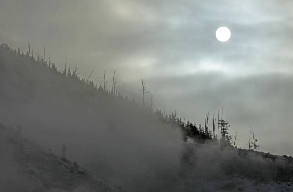 Sunrise through mist and clouds over a hill in Yellowstone National Park