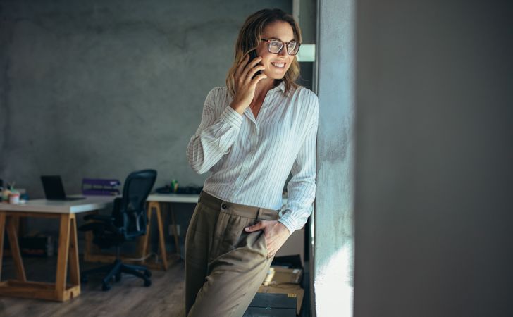 Woman talking on smart phone in office looking away from camera