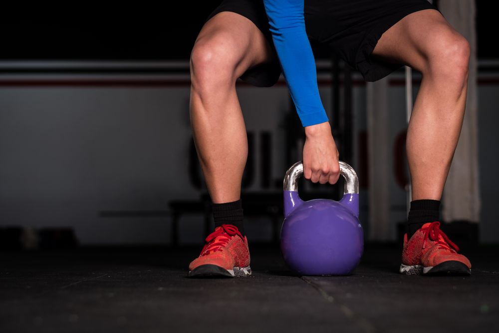 Man holding kettlebell on floor in gym