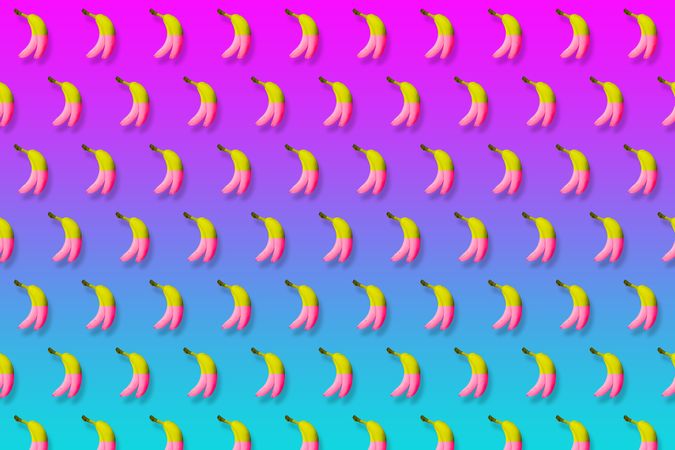 Pink and yellow bananas in rows on gradient pink to blue background