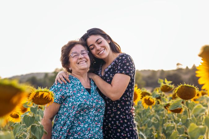 Grandmother and granddaughter in a field of sunflowers.
