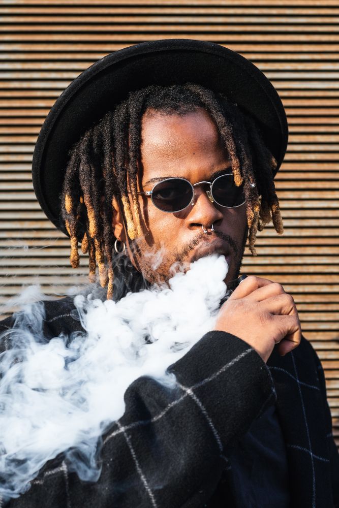 Trendy Black man in hat smoking