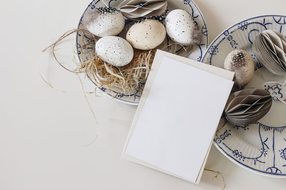 Top view of two blue floral bowls with traditional speckled eggs with feather isolated on table