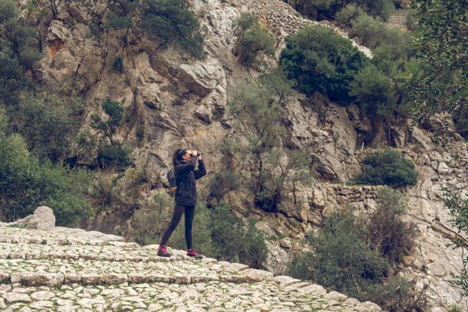 Traveler woman looking at binoculars admiring massive mountains