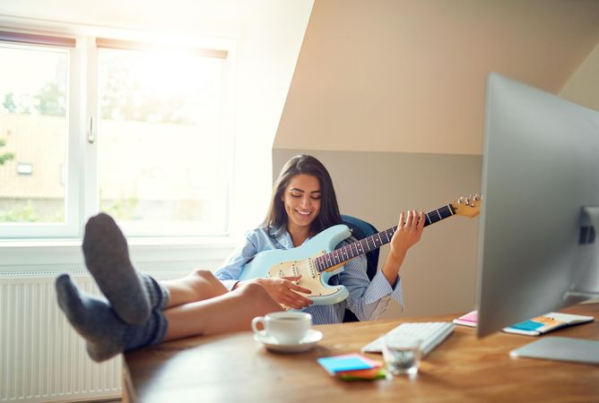 Woman having fun with guitar at her desk