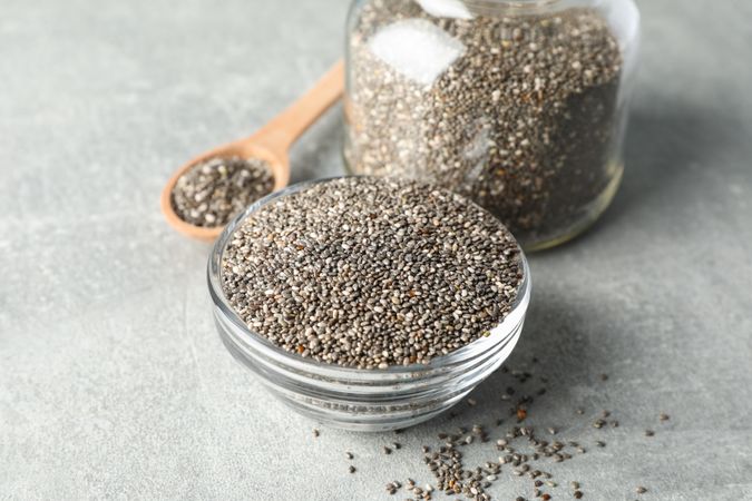 Glass tableware with seeds on grey table, space for text