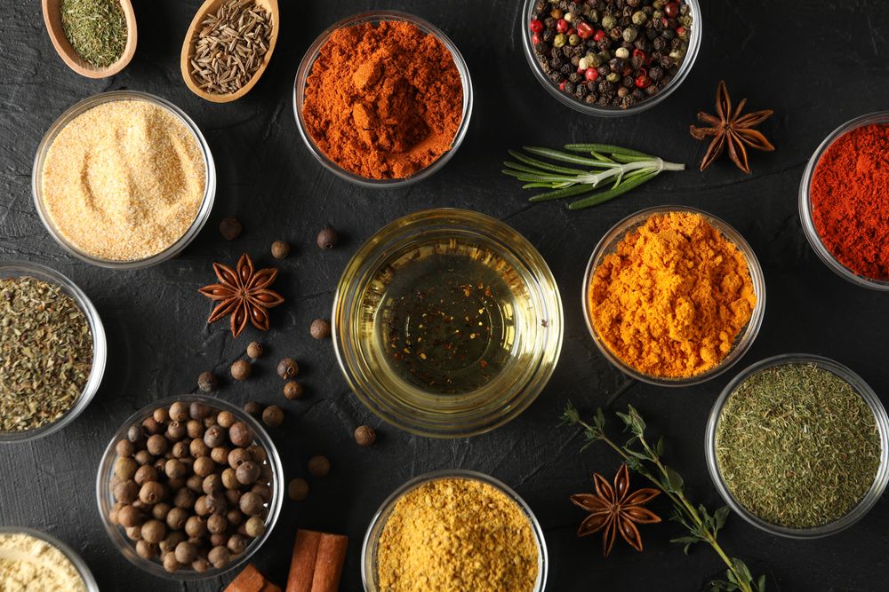Glass bowls full of spices arranged on dark table
