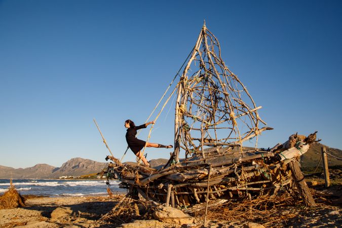 Young woman on decorative wooden ship near water on shore
