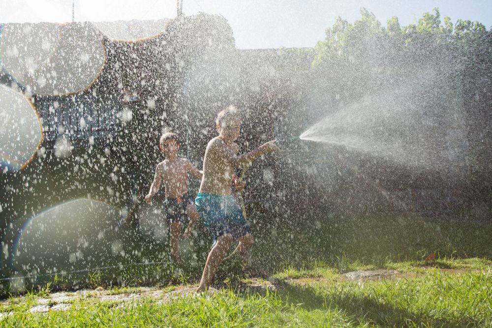 Little kids in swimwear having fun with splashing water