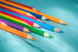 Coloured pencils arranged in a circle on a wooden background