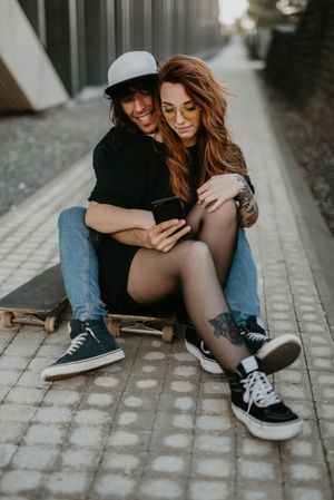 Skaters sitting on road on smartphone