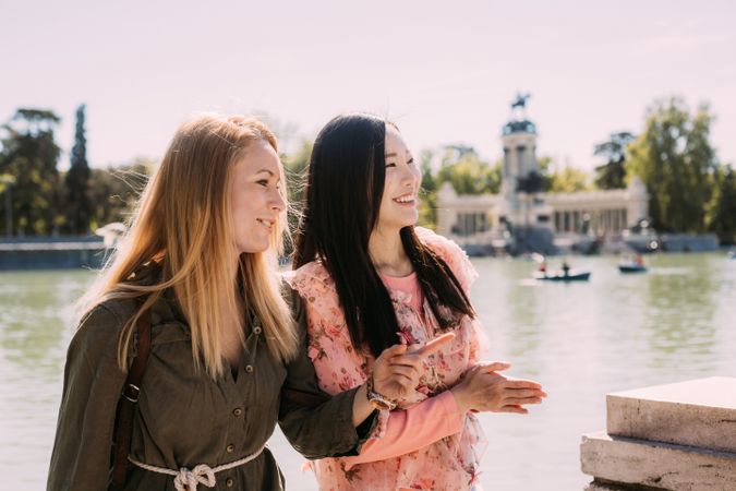 Cheerful multiracial friends sitting on embankment