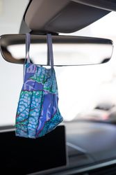Blue patterned coronavirus mask hanging on car mirror