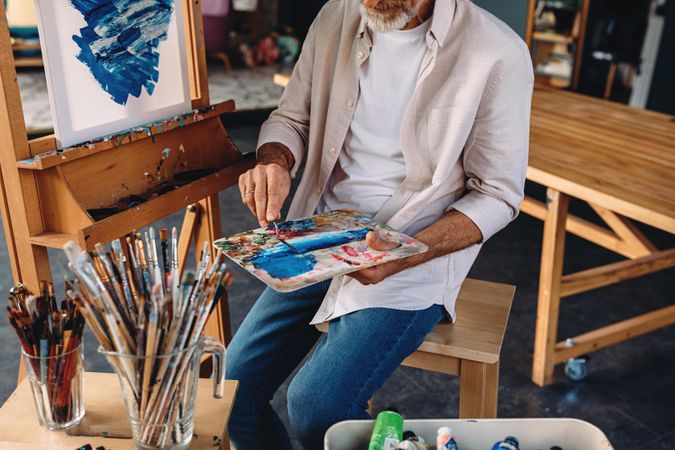 Man mixing blue paint on palette in artist studio