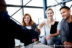 Smiling female business associates shaking hands at an informal meeting in an office 49xrL5