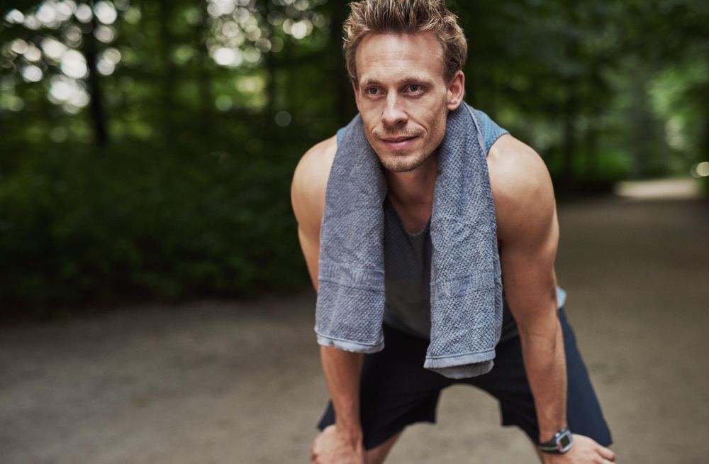 Sporty man leaning down with towel around neck