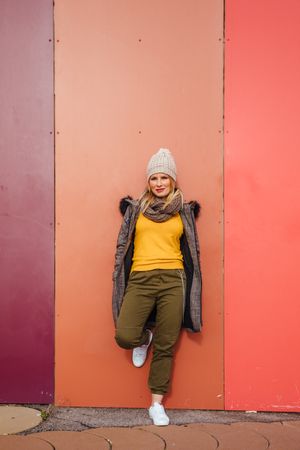 Blonde woman leaning on a colorful wall